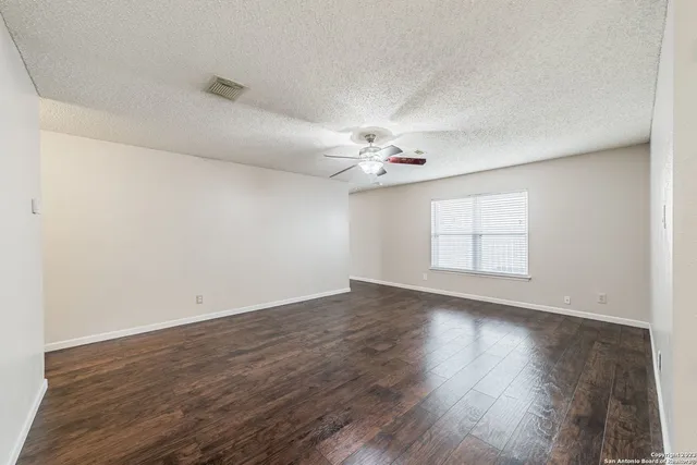 an empty room with wooden floor and fan