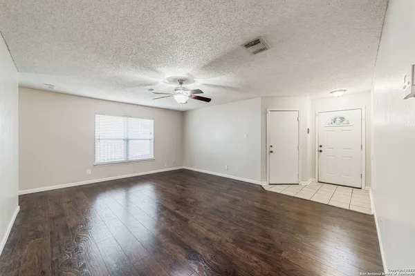 an empty room with wooden floor chandelier and windows