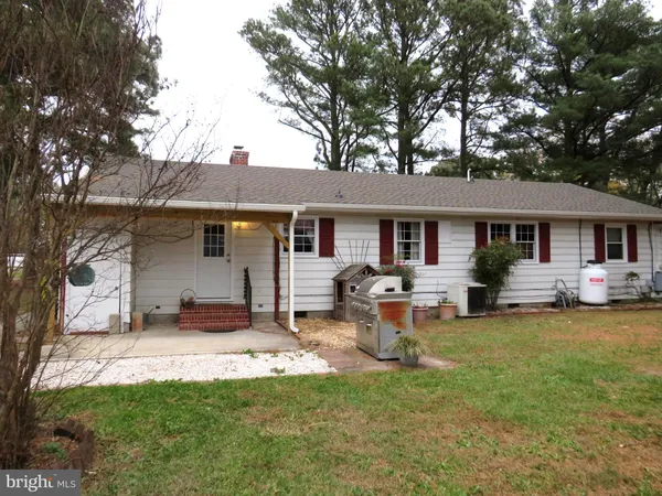 a front view of a house with a garden and trees