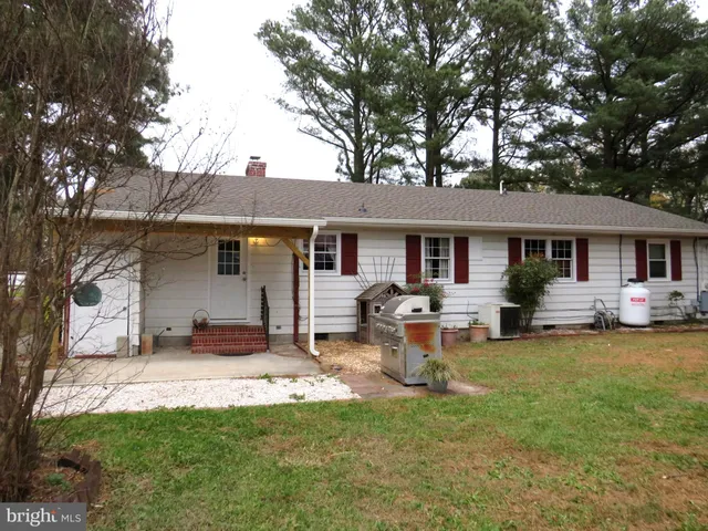 a front view of a house with a garden and trees