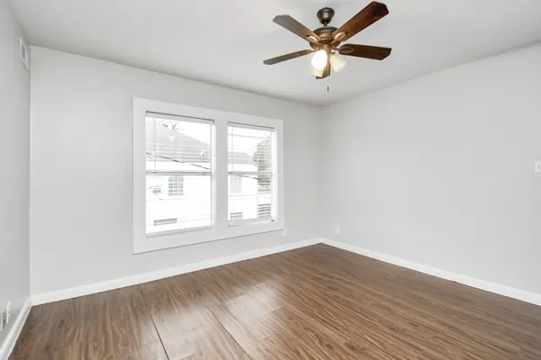 a view of empty room with wooden floor and ceiling fan