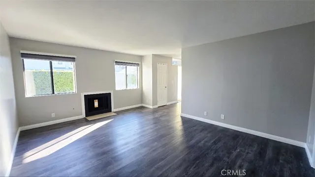 an empty room with wooden floor fireplace and windows