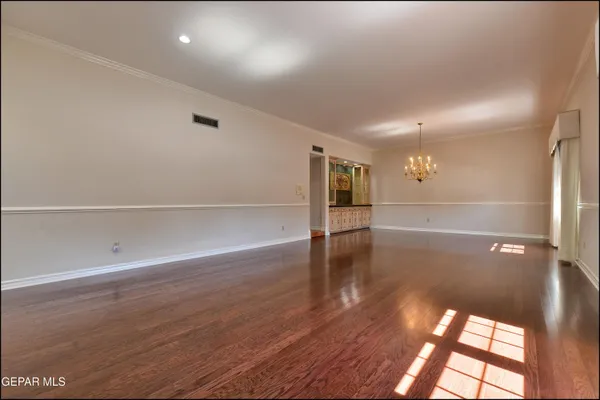 a view of a room with wooden floor chandelier and windows