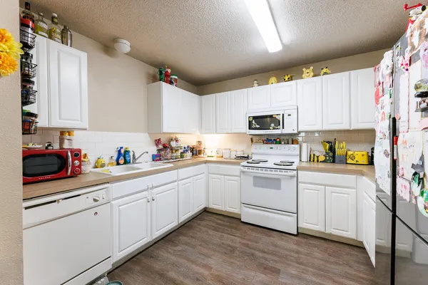 a kitchen with granite countertop white cabinets and white appliances