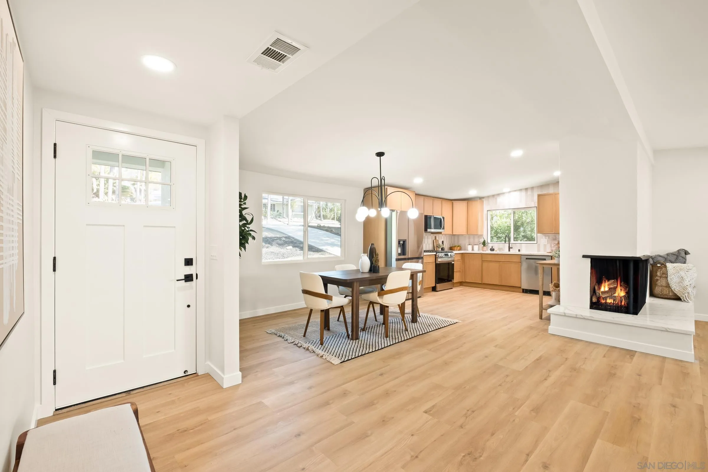 557 Sunset Drive Vista, CA 92081 - Photo 11 of 36 a living room with furniture a fireplace and a dining table with wooden floor