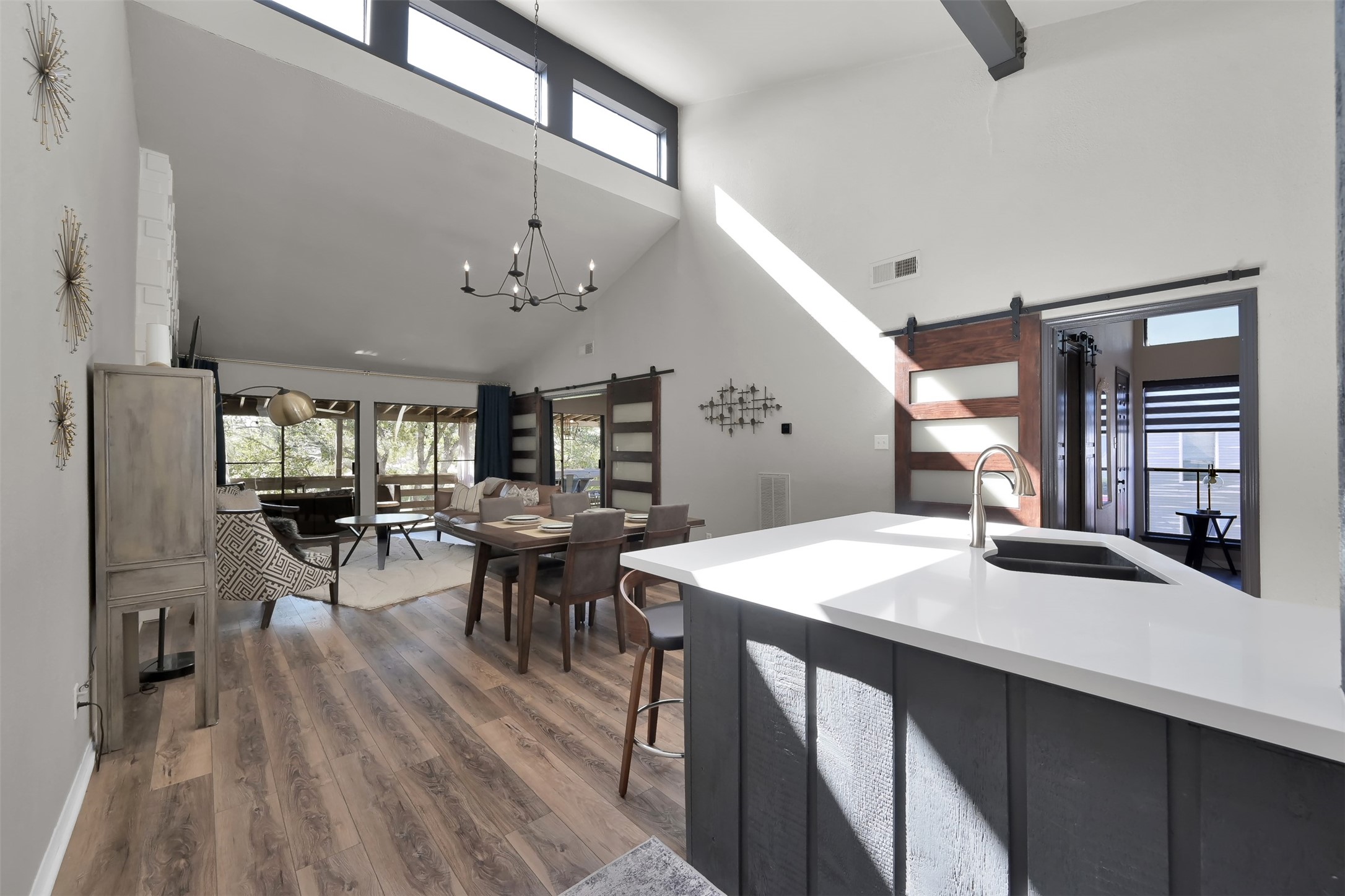 184 April Point Drive North Conroe, TX 77356 - Photo 4 of 41 Step inside to your open concept kitchen, dining and living room with a secondary bedroom off the kitchen and primary toward the porch designated by stylish barn doors and all with recently updated Vinyl plank flooring & designer lighting. The kitchen has updated fixtures, a granite sink and a huge bar area with quartz countertops