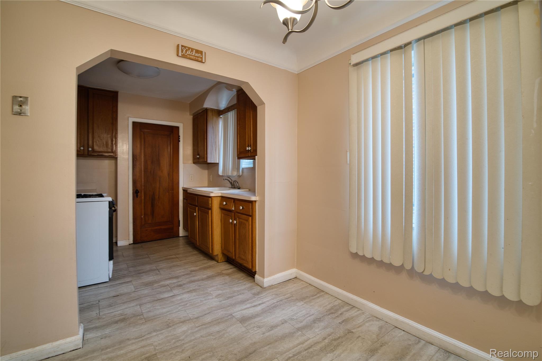 13644 Castleton Street Detroit, MI 48227 - Photo 6 of 18 Archway entry with wood-finish flooring, vertical blinds, and a built-in kitchen featuring wood cabinetry and white countertops