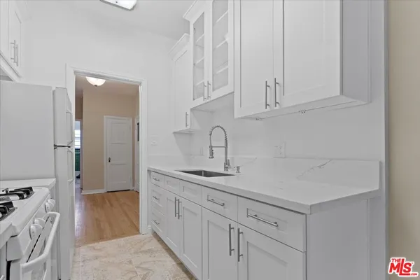 a kitchen with white cabinets and sink