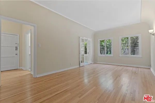 an empty room with wooden floor and windows
