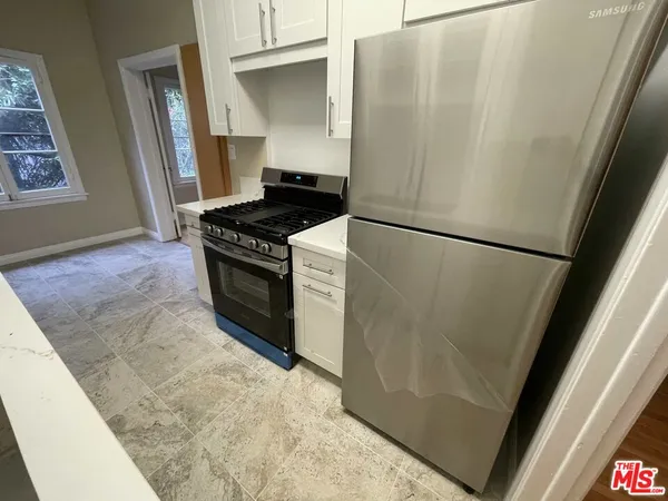 a kitchen with a refrigerator a stove and white cabinets