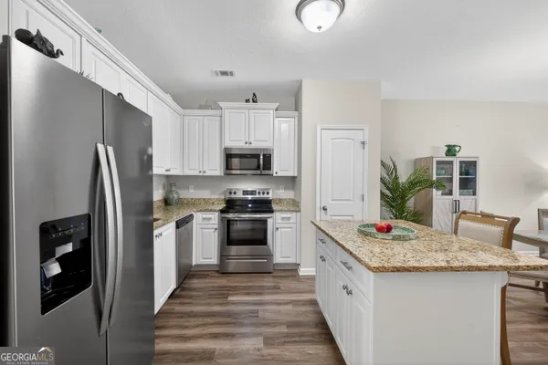 a kitchen with stainless steel appliances kitchen island granite countertop a refrigerator a stove and a sink