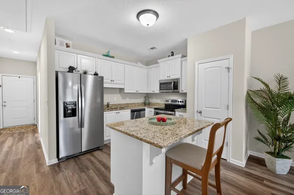 a kitchen with stainless steel appliances granite countertop a refrigerator a stove a sink dishwasher a dining table and chairs with wooden floor