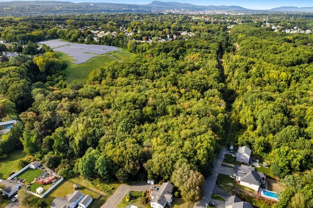 an aerial view of residential houses with outdoor space and trees