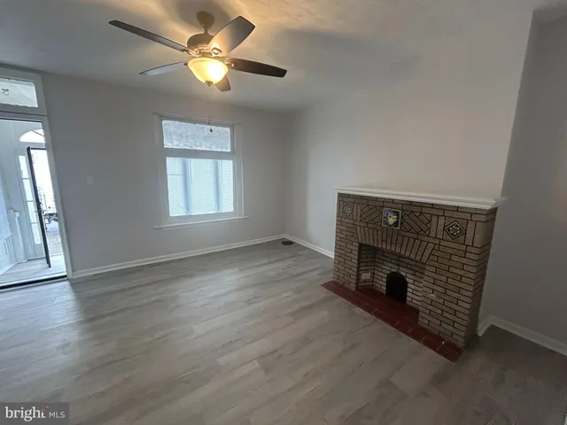 an empty room with wooden floor a chandelier fan and windows