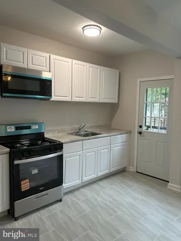 a kitchen with granite countertop a stove top oven a sink dishwasher and cabinets with wooden floor