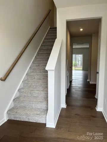 a view of a hallway with wooden floor and staircase