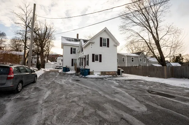 a view of a white house with a bed covered by side of the road
