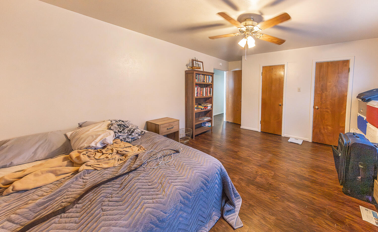 2408 33rd Street Lubbock, TX 79411 - Photo 12 of 31 a spacious bedroom with a bed and a bookshelf with wooden floor