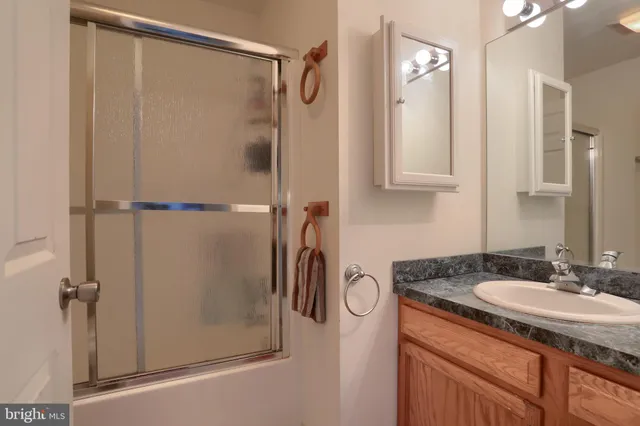 a bathroom with a granite countertop shower sink and mirror