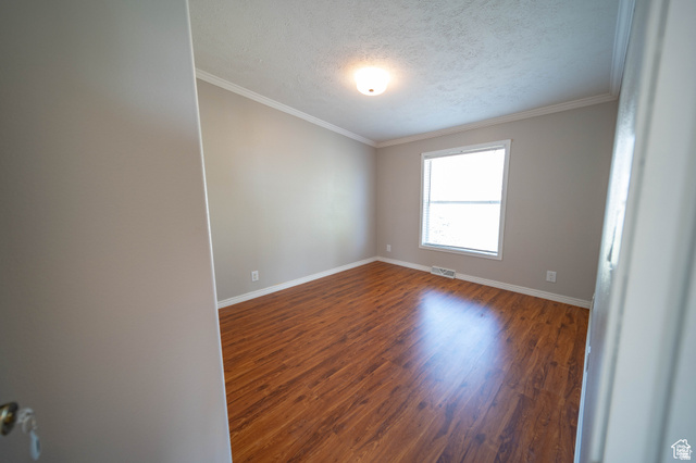 1407 North 1250th Street West Helper, UT 84526 - Photo 13 of 27 Bedroom 1 with dark wood-style floors, a textured ceiling, and ornamental molding