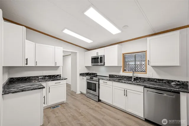 a kitchen with stainless steel appliances granite countertop a stove a sink and white cabinets