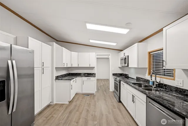 a kitchen with stainless steel appliances granite countertop a stove top oven a sink dishwasher a refrigerator and cabinets with wooden floor