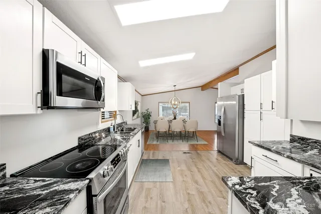 a kitchen with stainless steel appliances a stove a sink a refrigerator and a microwave