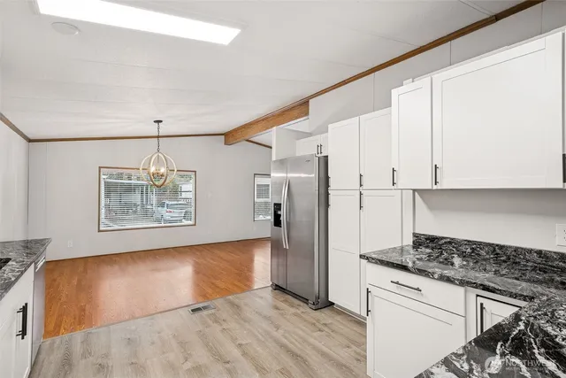 a kitchen with granite countertop white cabinets and refrigerator