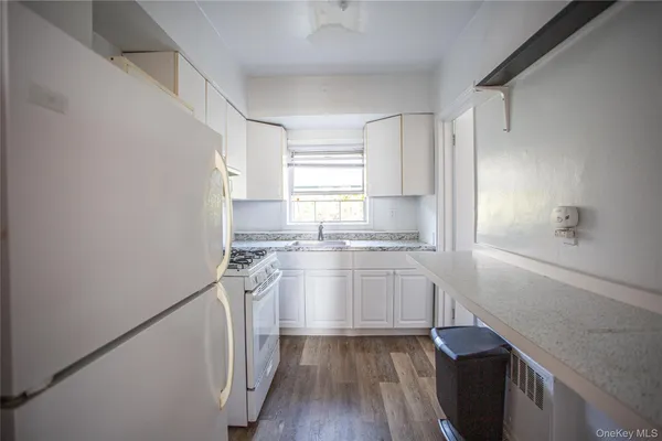 a kitchen with granite countertop white cabinets and white appliances