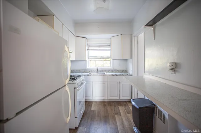 a kitchen with granite countertop white cabinets and white appliances