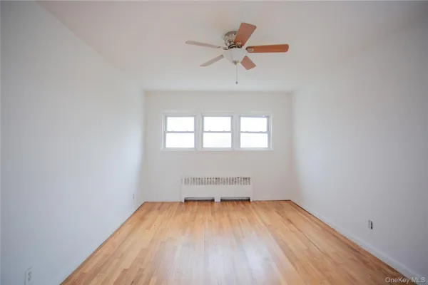 an empty room with a window and a ceiling fan