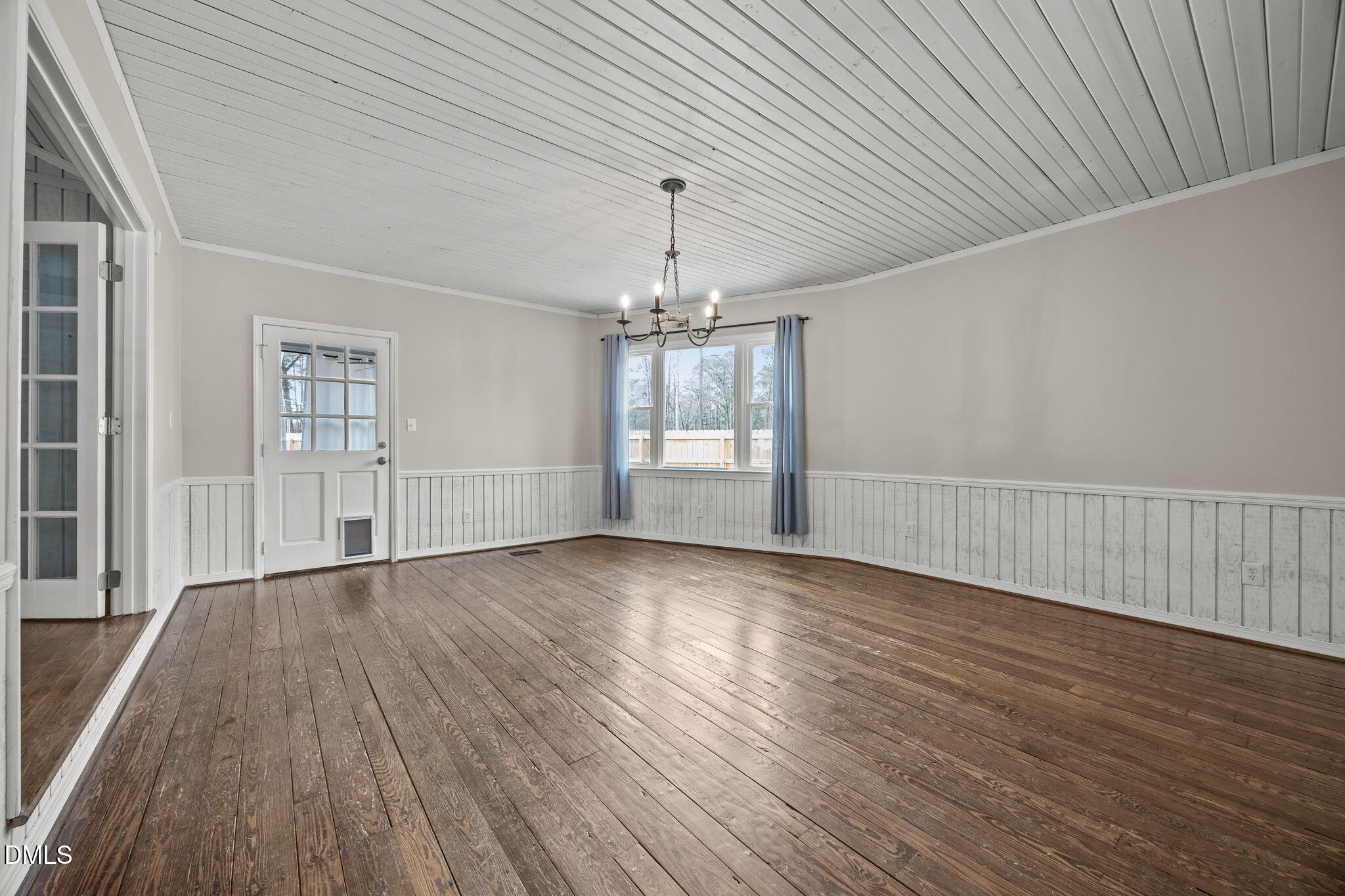 700 Woodland Road Raleigh, NC 27603 - Photo 8 of 35 an empty room with wooden floor chandelier and windows