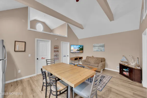 a dining area with stainless steel appliances kitchen island granite countertop a dining table chairs and a refrigerator