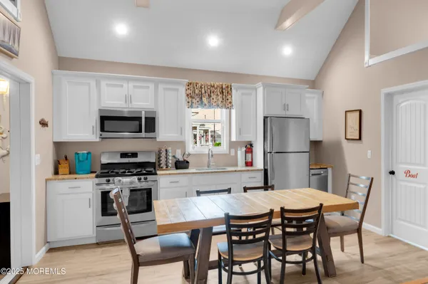 a kitchen with stainless steel appliances a refrigerator a stove a dining table and chairs