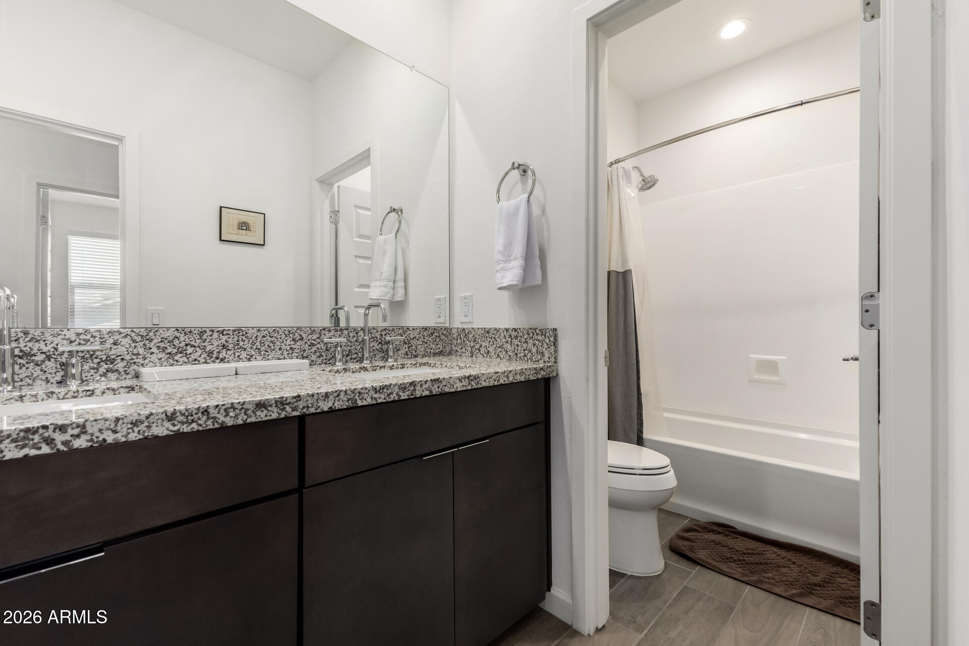 15544 South 181st Lane Goodyear, AZ 85338 - Photo 21 of 46 a bathroom with a granite countertop sink toilet mirror and a bathtub