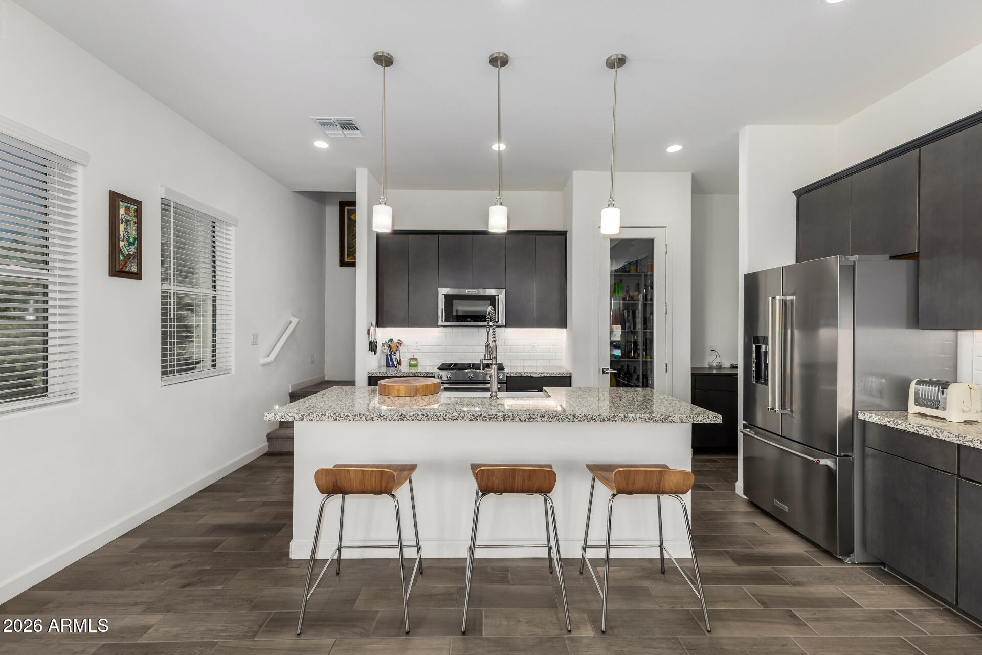 15544 South 181st Lane Goodyear, AZ 85338 - Photo 10 of 46 a kitchen with stainless steel appliances granite countertop a table chairs and a refrigerator