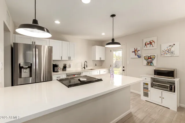a kitchen with stainless steel appliances a stove a refrigerator and white cabinets