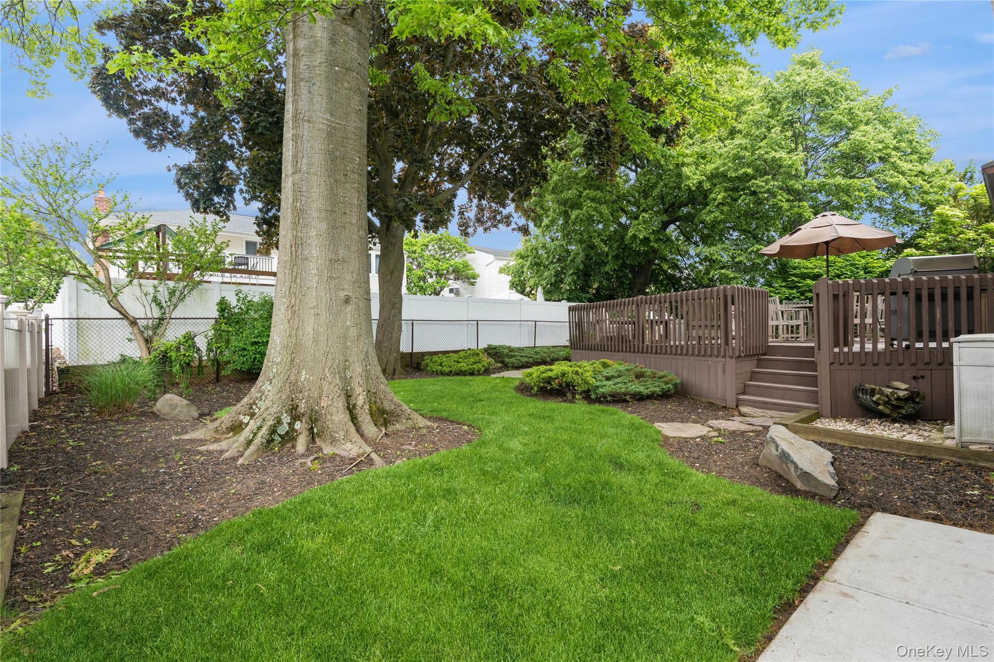 2772 Riverside Avenue Merrick, NY 11566 - Photo 28 of 45 a view of a backyard with table and chairs plants and wooden fence