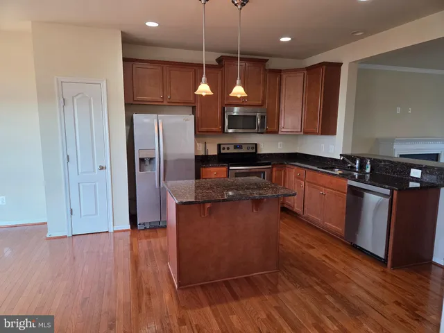 a kitchen with stainless steel appliances granite countertop wooden floors and granite counter tops