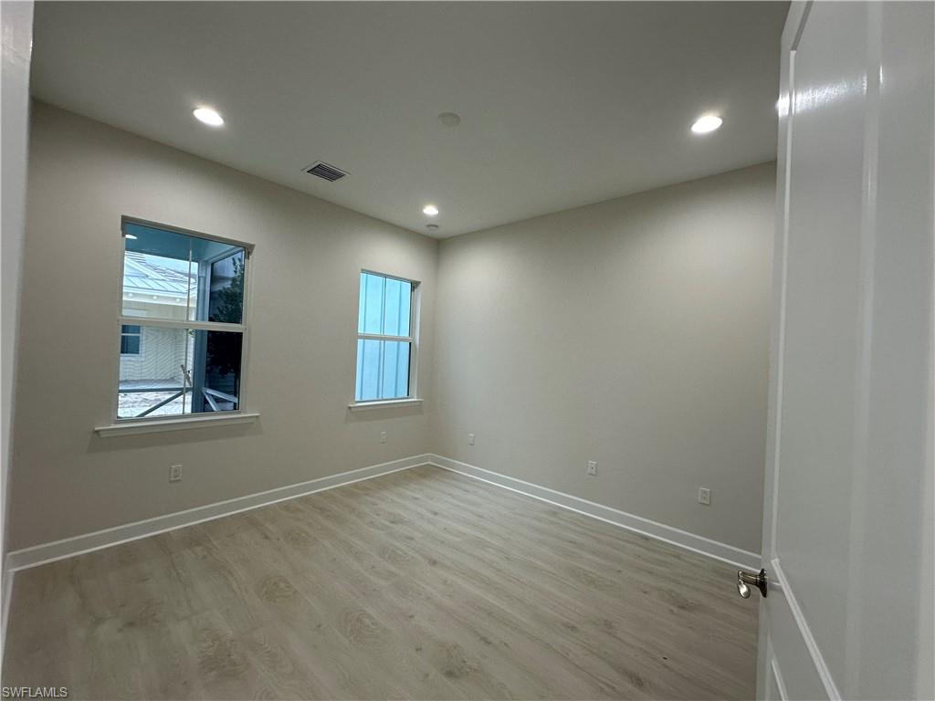 7255 Saona Court Naples, FL 34113 - Photo 17 of 28 an empty room with wooden floor and windows