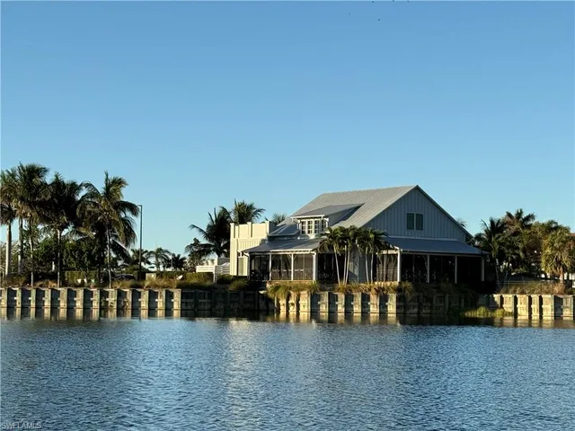a front view of house with lake view and trees in the background
