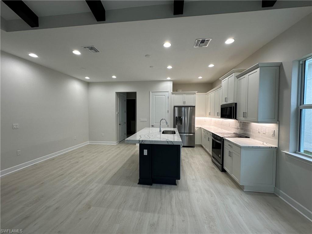 7255 Saona Court Naples, FL 34113 - Photo 5 of 28 a large white kitchen with a stove a sink dishwasher and a refrigerator with wooden floor