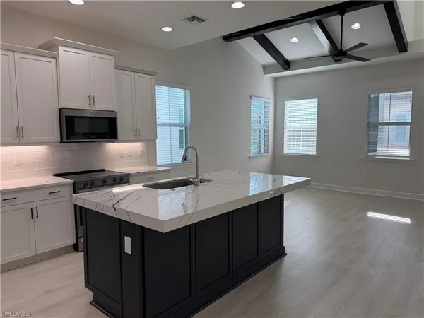 a large white kitchen with a stove a sink dishwasher and a refrigerator with wooden floor