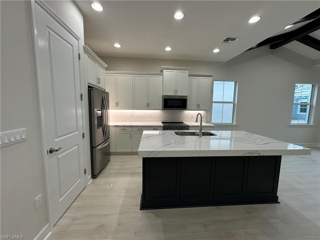 7255 Saona Court Naples, FL 34113 - Photo 7 of 28 a kitchen with stainless steel appliances a sink stove and refrigerator