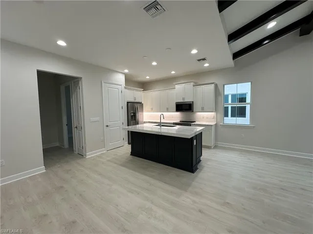 a large kitchen with a large counter top stainless steel appliances and cabinets