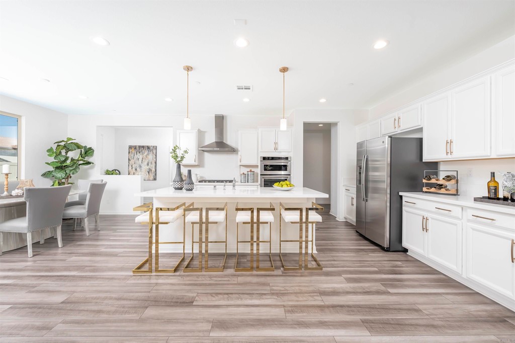 33288 Skyview Road Winchester, CA 92596 - Photo 8 of 51 a kitchen with stainless steel appliances kitchen island granite countertop a dining table chairs and a refrigerator