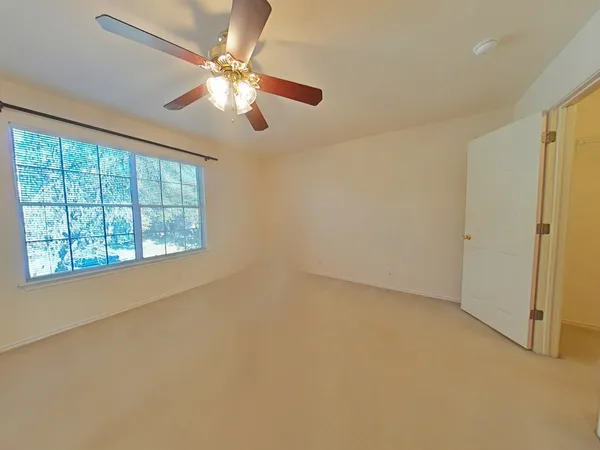 an empty room with windows and fan
