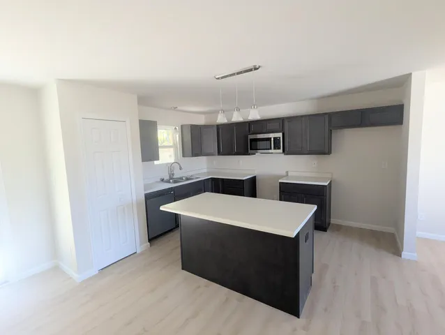 a large white kitchen with sink a refrigerator and white cabinets
