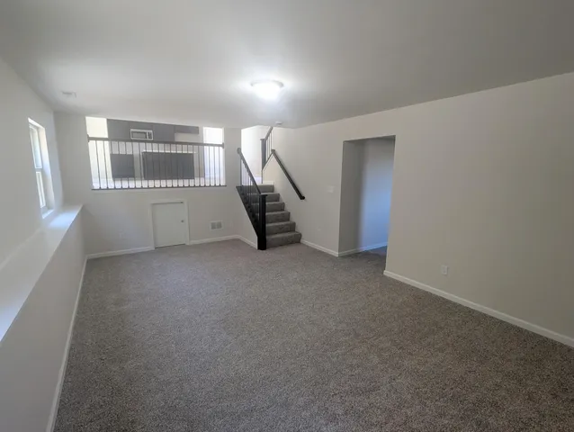 a view of empty room with stairs and wooden floor