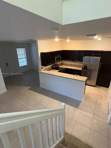 a view of kitchen with stainless steel appliances wooden floor